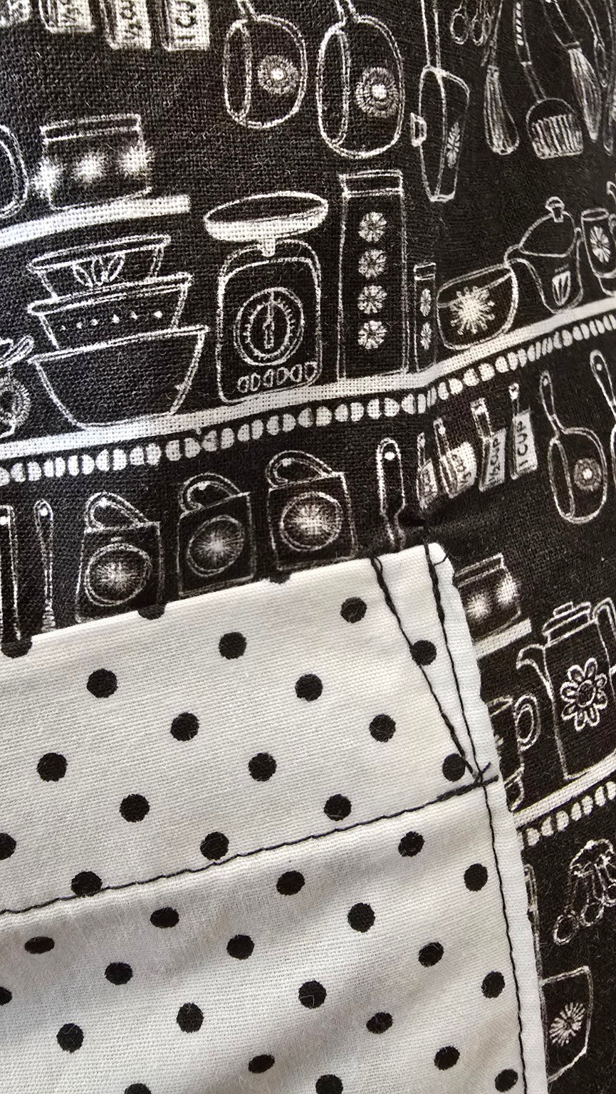 Close-up of black kitchen utensil print and white polka dot accent on Classic Kitchen apron