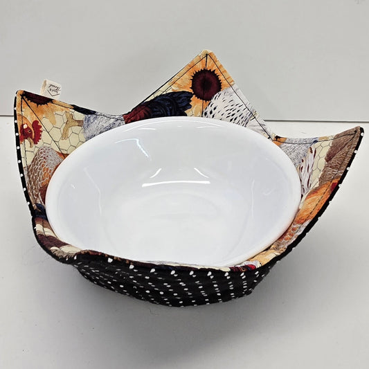 Hen House reversible bowl cozy cradling a white bowl, chicken and sunflower print with black polka dot reverse