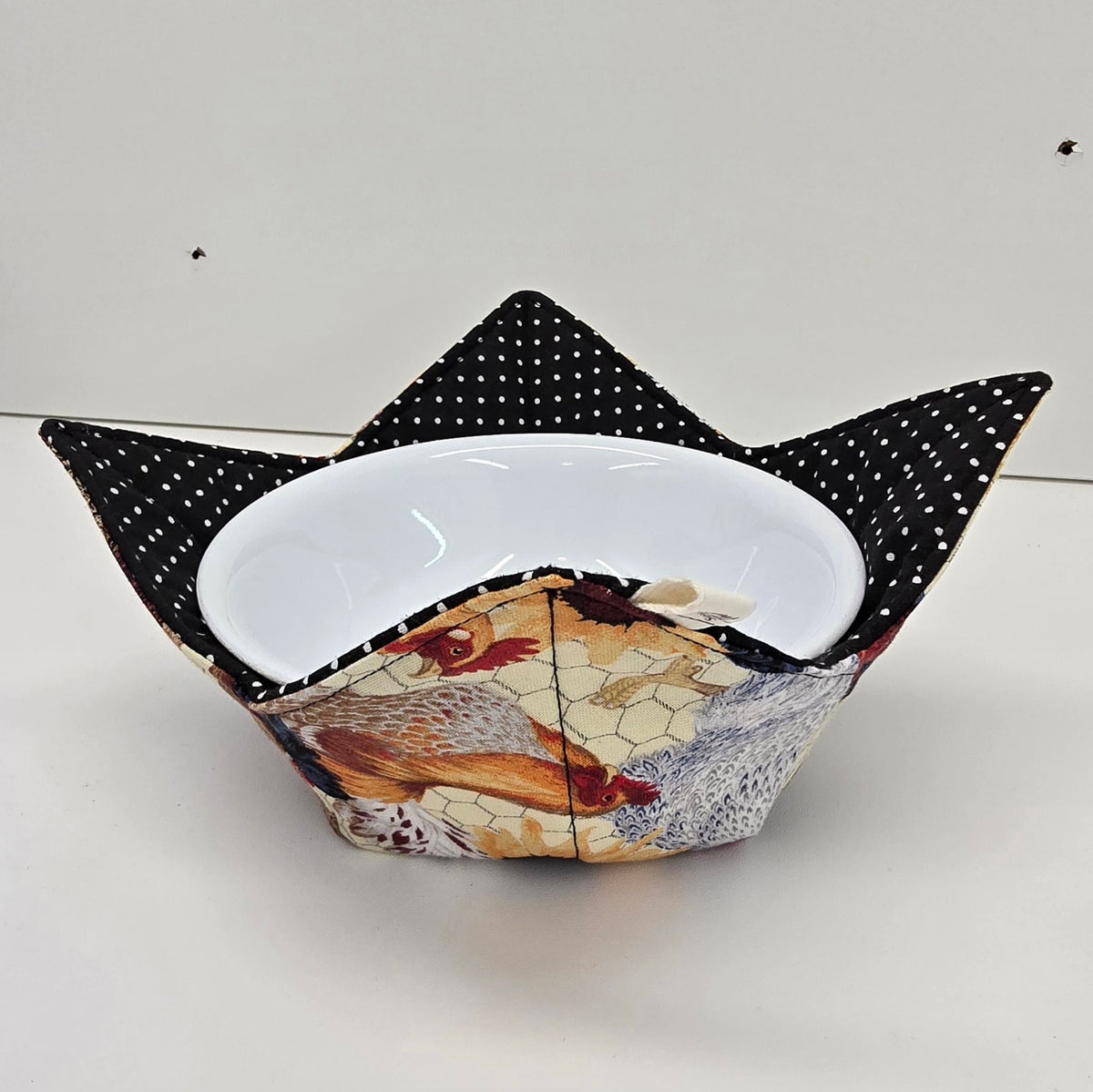 Hen House reversible bowl cozy shown from the side with black and white polka dot lining