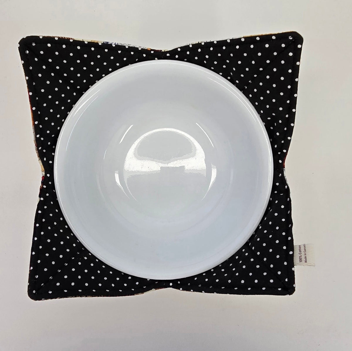 Top view of Hen House reversible bowl cozy with black and white polka dot side up