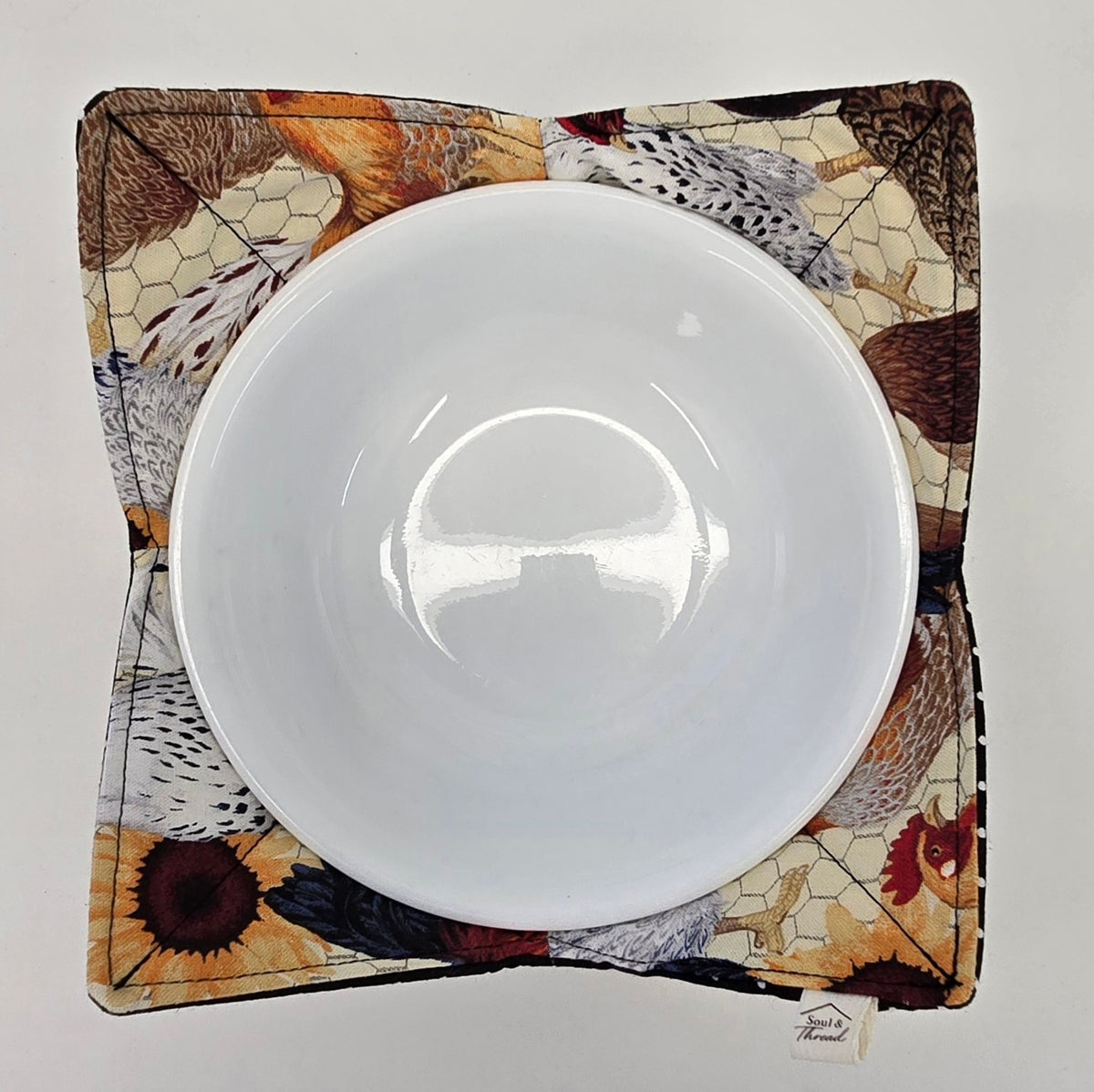 Top view of Hen House reversible bowl cozy with chicken print side up