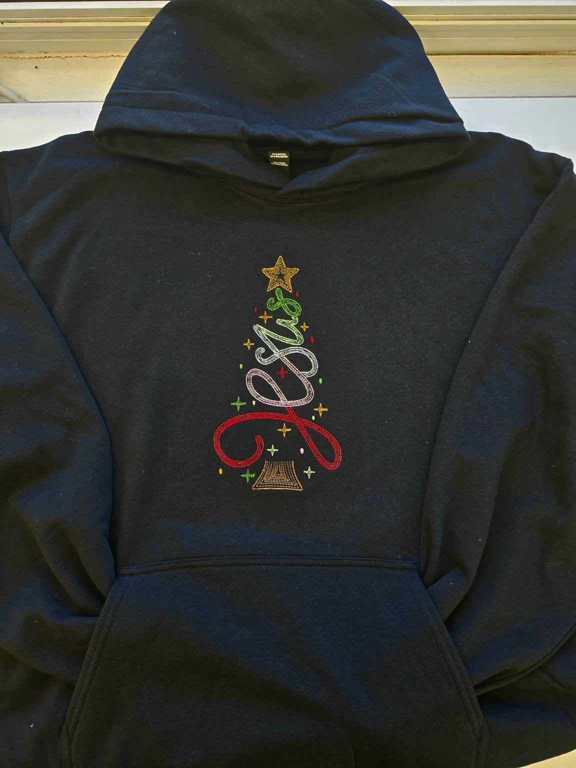 Close view of Jesus Christmas embroidery on black pullover hoodie
